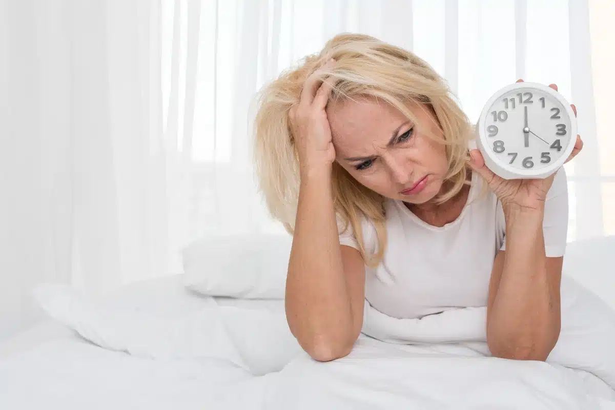Donna insonne a letto che guarda l'orologio, concetto di disturbi del sonno